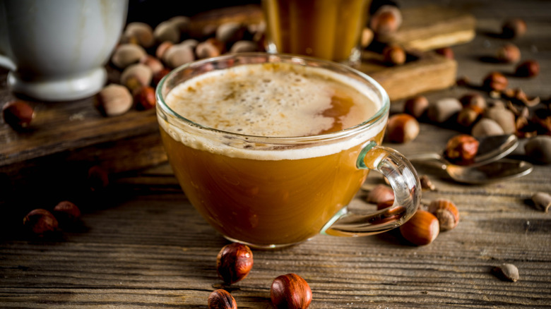 Latte in a mug surrounded by hazelnuts