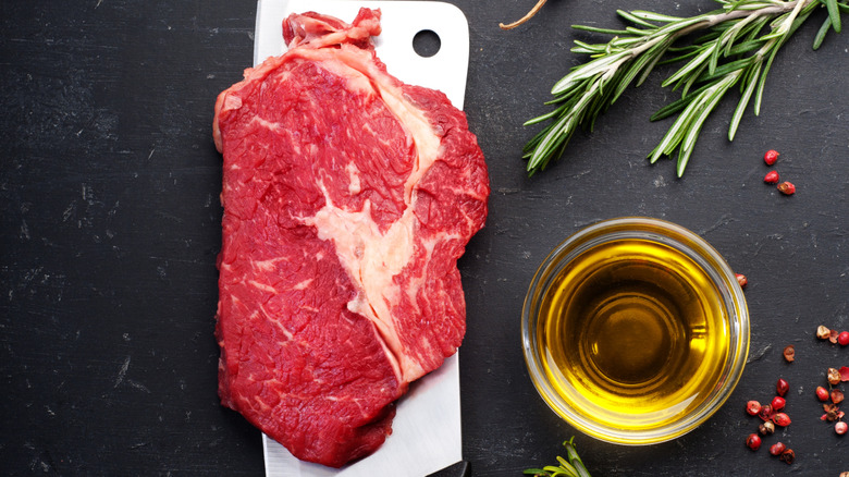 raw steak next to bowl of olive oil