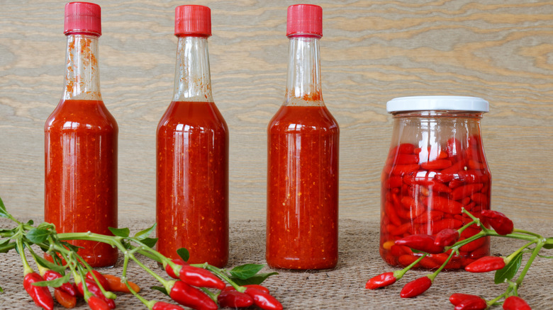 three bottles and a jar of fermented tabasco pepper hot sauce