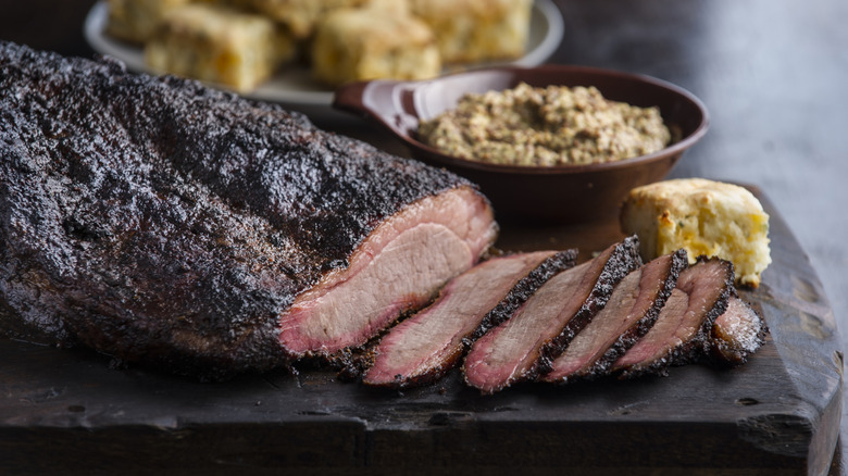 A smoked brisket sitting on a wood block with sides