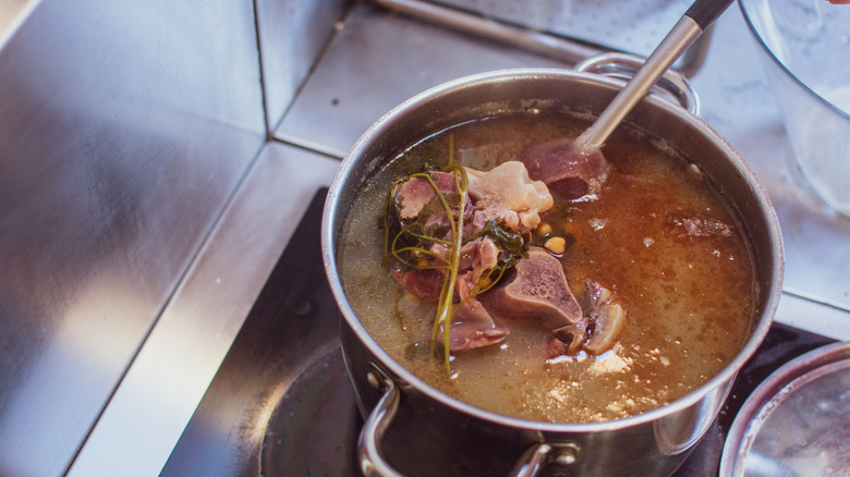 A pot of meaty soup on a stovetop.