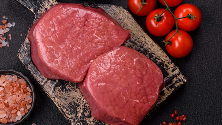 Two eye of round steaks surrounded by seasonings.