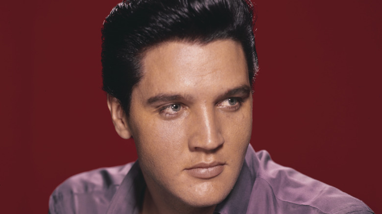 Elvis Presley wearing a purple shirt looking away from the camera