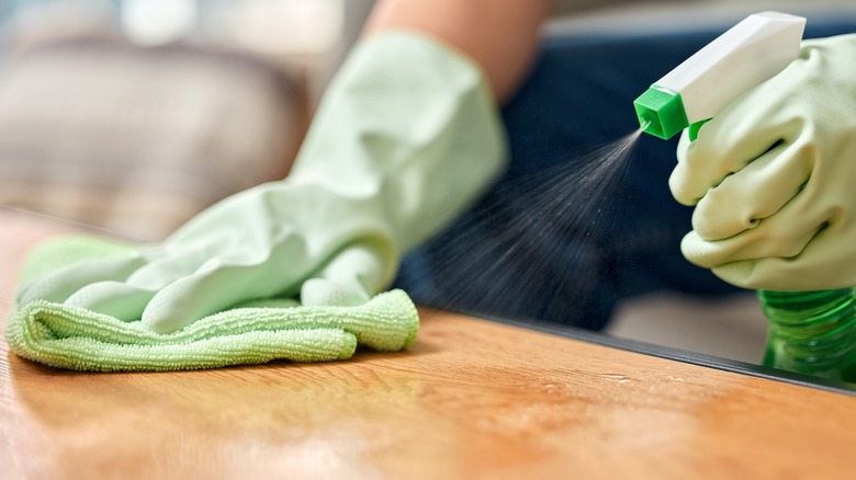 A woman sprays cleaning solution on wood counter