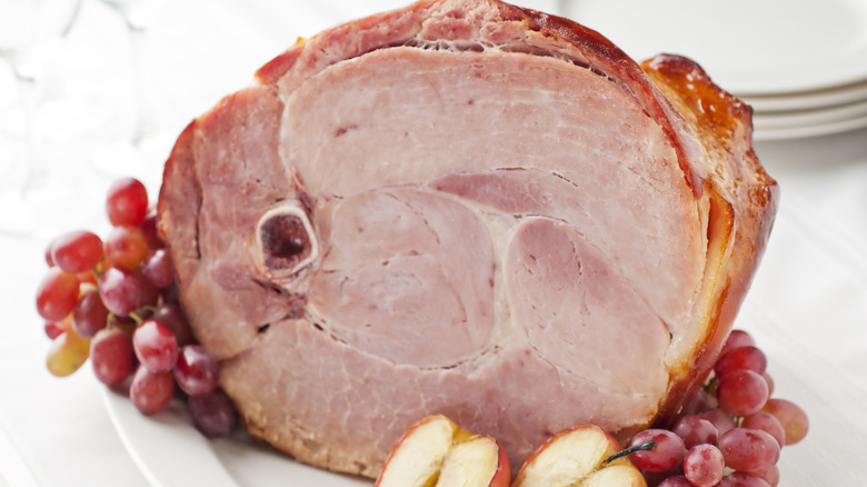 Bone-in Easter ham on a dinner table with fruits