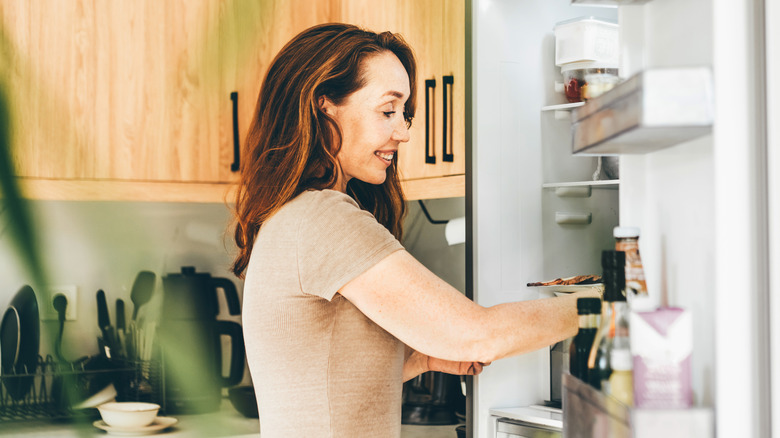 Woman taking food out of a refrigerator.