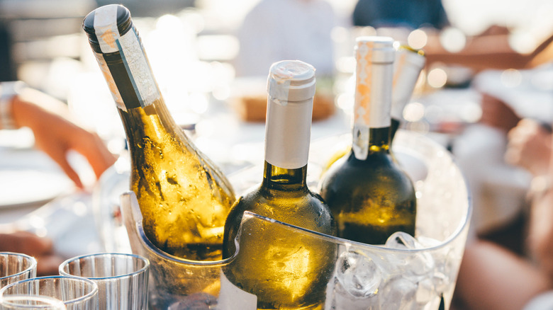 Three wine bottles sitting in a bucket of ice on a table