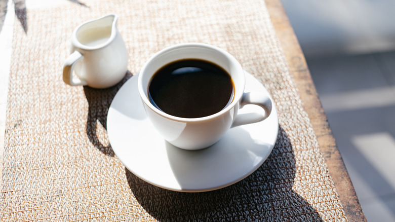 Cup of coffee on saucer with creamer