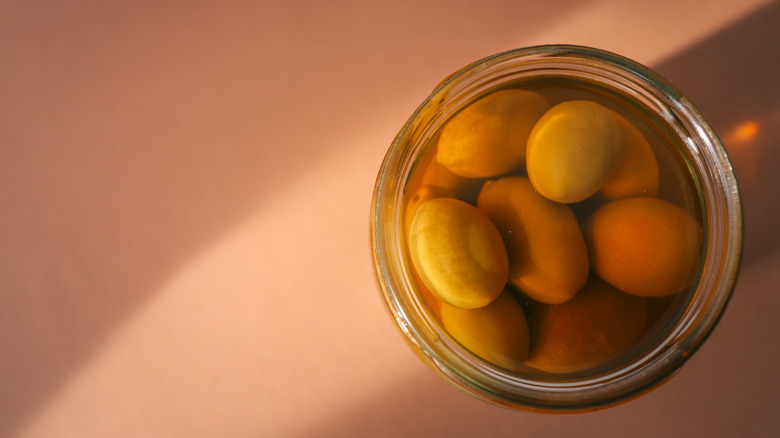 An open jar of green olives in brine sitting on a table