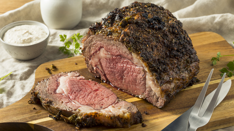 Roasted, boneless prime rib beef roast, sliced thick on a cutting board
