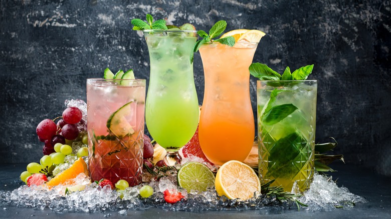 colorful cocktails surrounded by fruit and ice