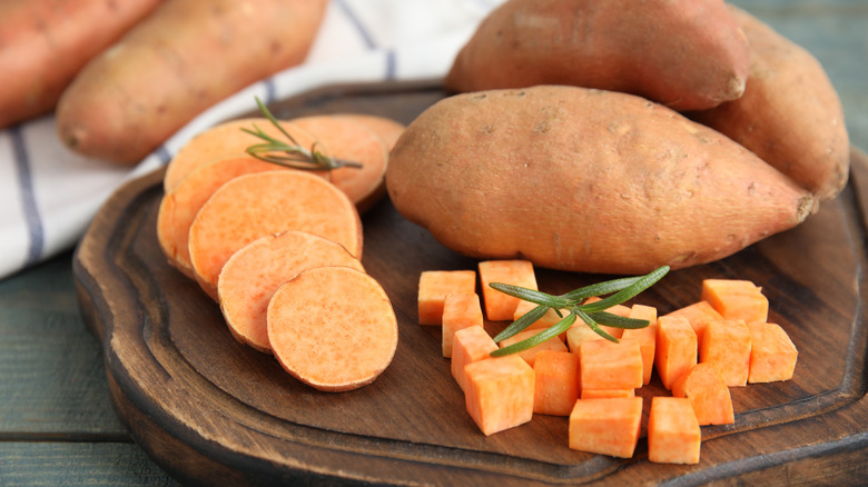 Cut and whole sweet potatoes on a board