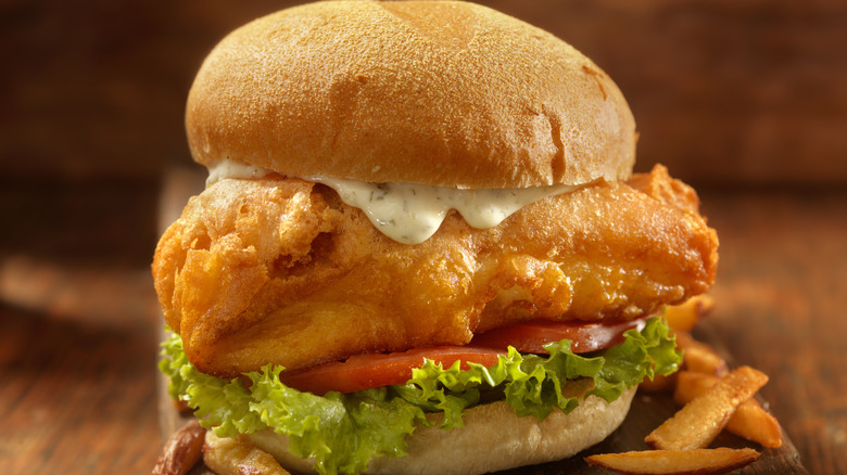 A fish sandwich with tomato and tartar sauce