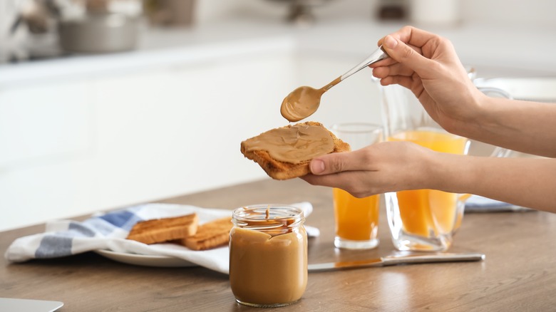 person spreading nut butter onto toast in kitchen