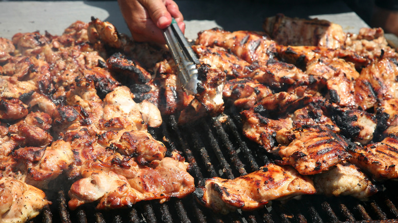 person flipping chicken on a grill
