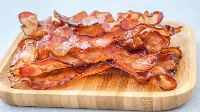 Fried bacon strips on a wooden board.