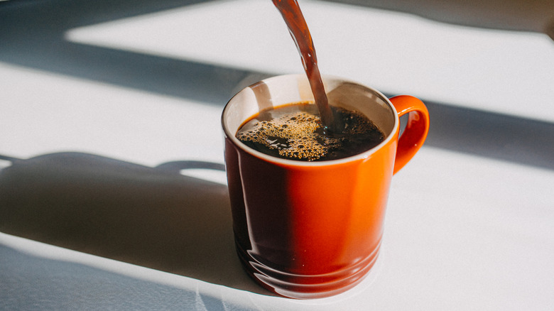Coffee pouring into an orange mug