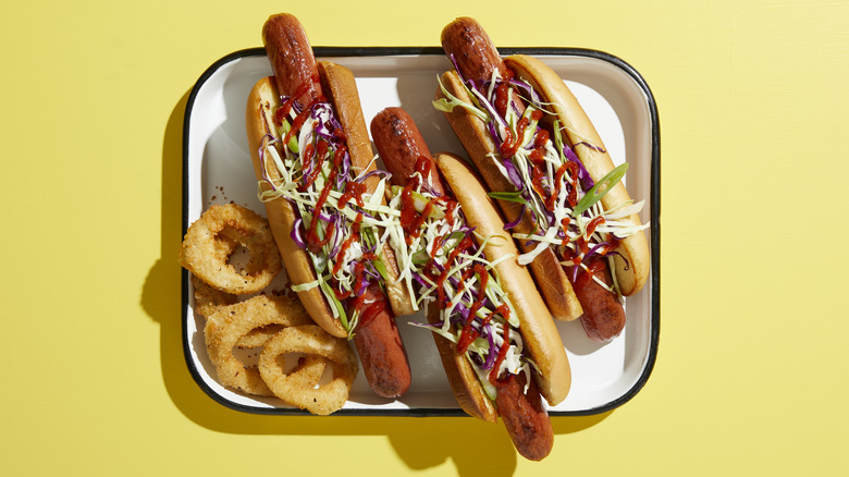 Three loaded hot dogs on a yellow background