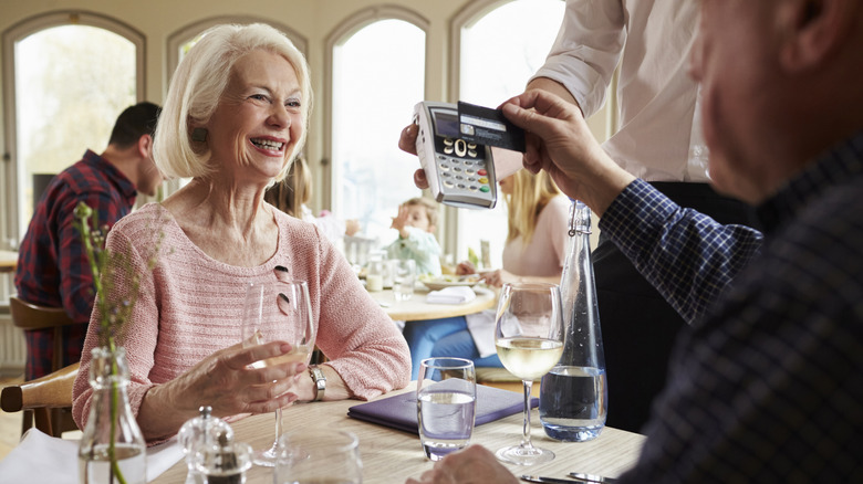 Senior citizens paying bill at restaurant