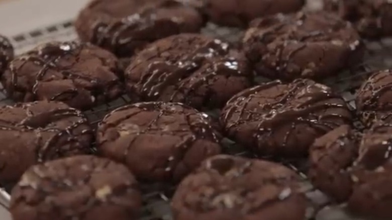 Several chocolate cookies drizzled with melted chocolate on a rack