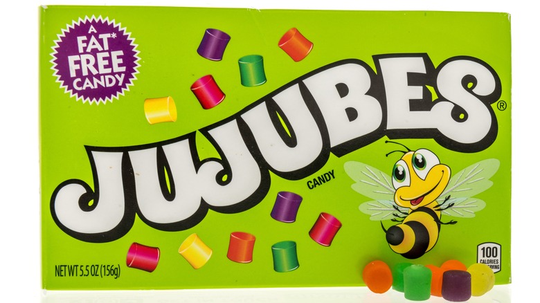 A green Jujubes candy box with seven Jujubes pieces in front on the lower right