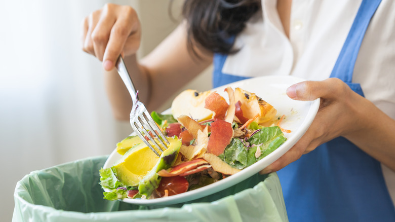 Person scraping leftover food into kitchen composter