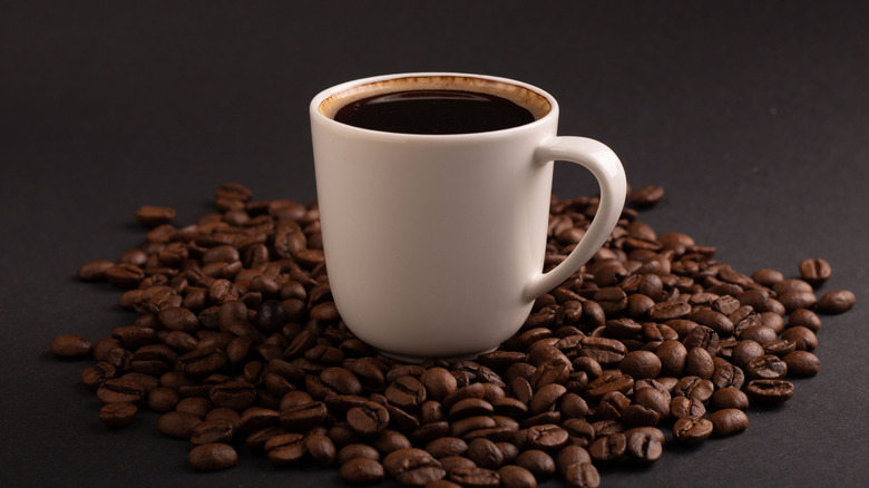 A cup of coffee next to coffee beans