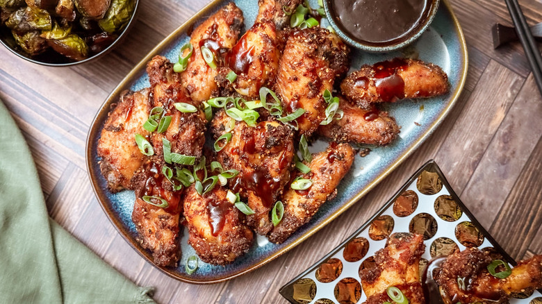 Korean dry-rubbed chicken wings on serving platter with scallions and dipping sauce