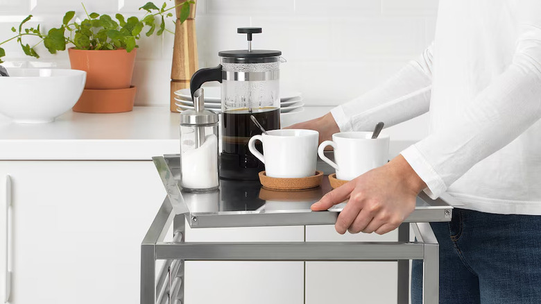 Stainless steel kitchen cart with French press and mugs