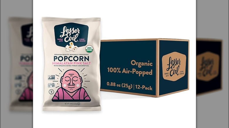 A bag of Lesser Evil popcorn in front of a box of popcorn bags