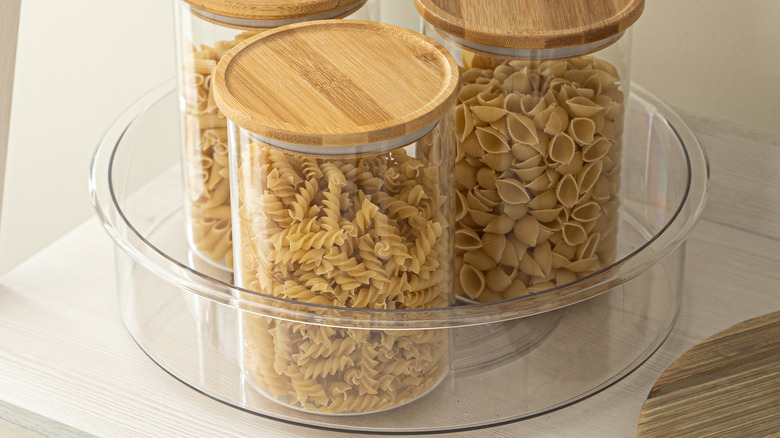 Glass jars containing different dry pastas on a plastic lazy Susan