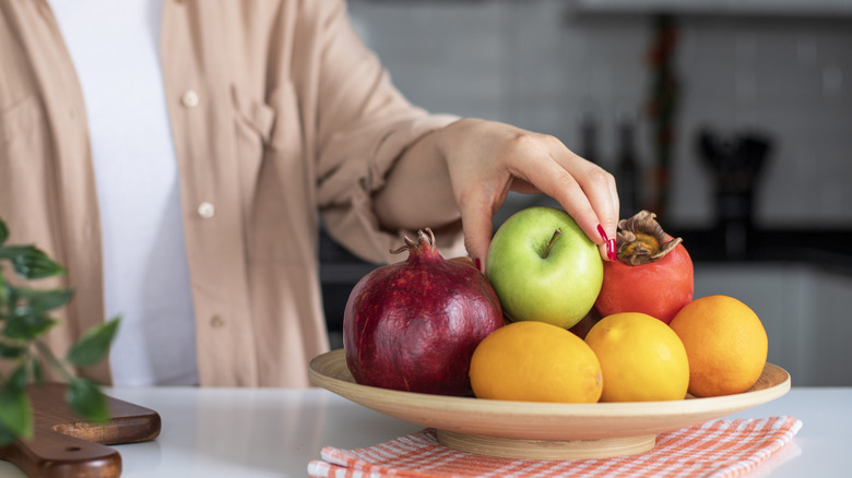 hand reaching for fruit bowl on kitchen island