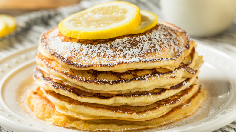 Stack of lemon ricotta pancakes topped with lemon slices on a plate
