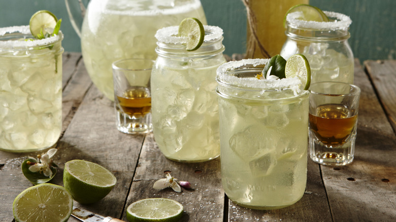 Mason jar margaritas and pitcher of margaritas with shots of tequila