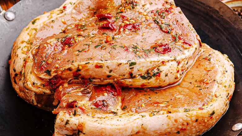 Two p ork chops marinating in flavored oil