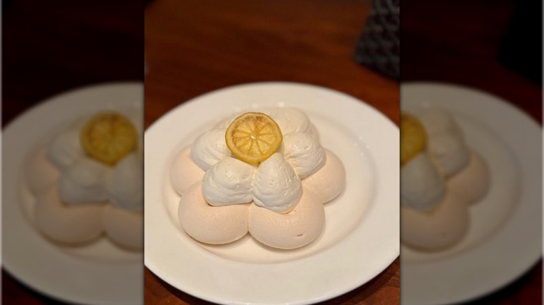 A lemon slice on a two-layer bed of meringue on a white plate