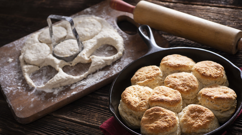 Pan of cooked biscuits, baking accessories, and fresh dough
