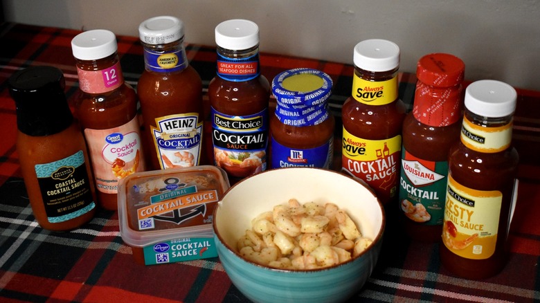 bottles of cocktail sauce surrounding a bowl of shrimp