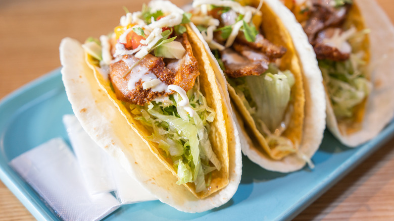 Three tacos on a blue tray