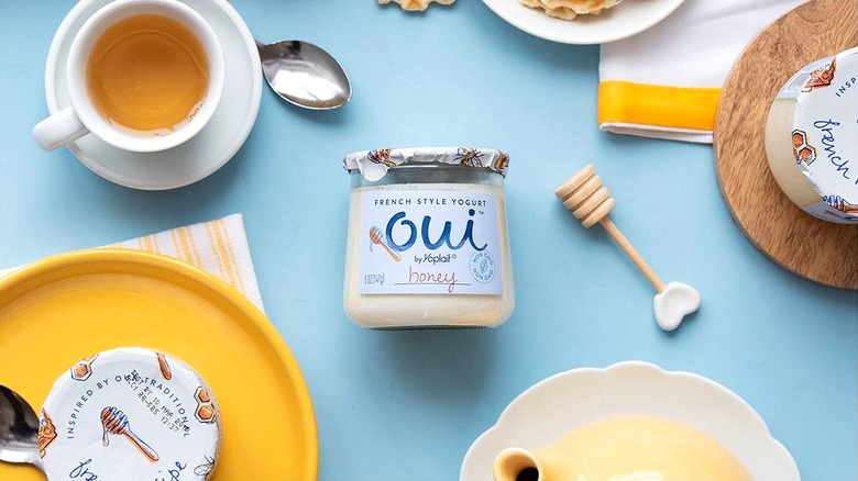 Jar of Oui by Yoplait honey flavored yogurt on a light blue surface