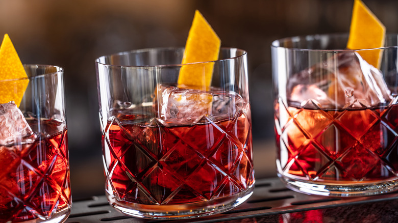 Three Negronis close up garnished with orange