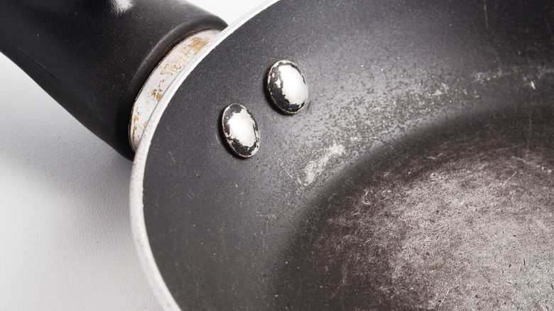Riveted pan handle of a frying pan with scratched nonstick surface