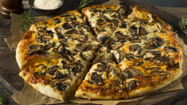 Mushroom pizza with fresh herbs on a wooden serving platter