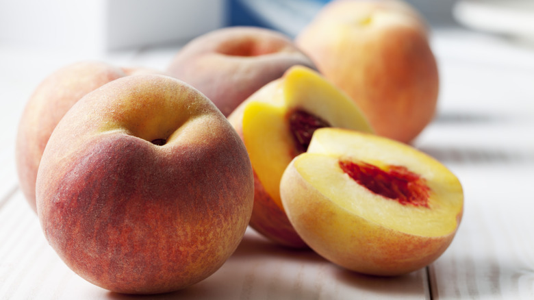 Whole and half peaches on wooden table