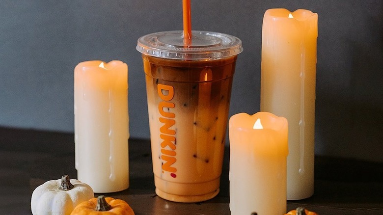 An iced Peanut Butter Cup Macchiato on a table with candles and mini pumpkins