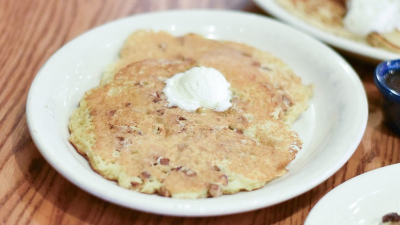 A white plate with pecan pancakes and butter
