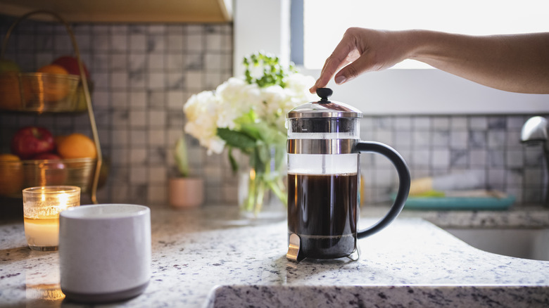 hand pushing down the plunger of a French press