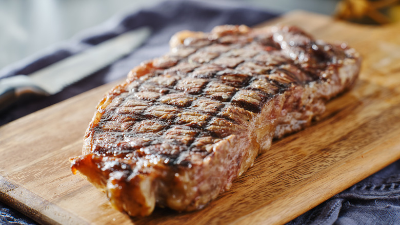 A new York strip steak resting on a cutting board