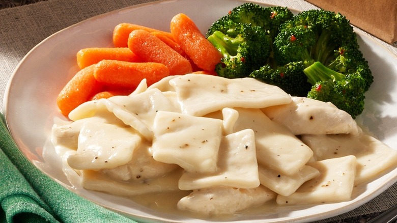 Plate of chicken and dumplings on white plate with carrots and broccoli