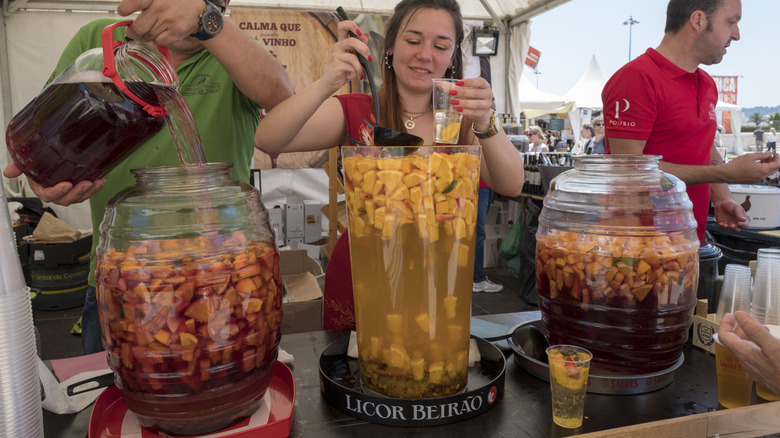 Man and woman with large jugs of sangria serving